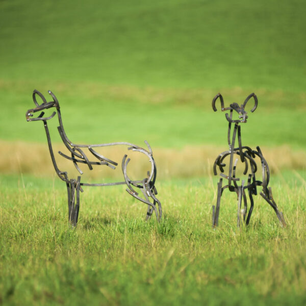 A pair of red calves sculpture standing alert in the fields